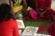 Indian women wearing saris looking at their artwork.