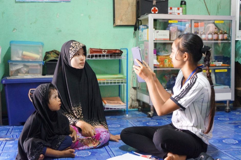 Woman and child speaking to M-FUND health worker in Thailand.